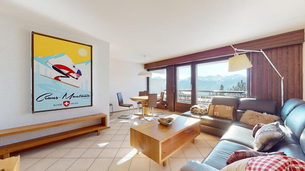 ein Wohnzimmer mit einem Sofa und einem Tisch in der Unterkunft Lovely apartment with a view - accessible by skis in Crans-Montana