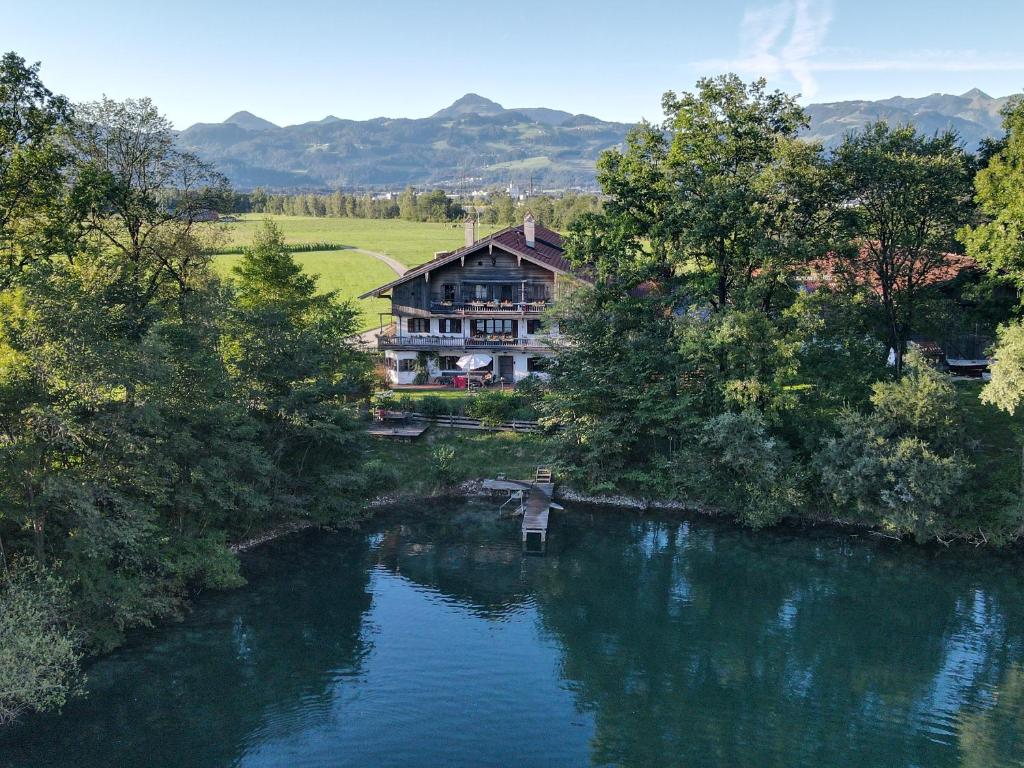 - une vue sur une rivière avec une maison en arrière-plan dans l'établissement Ferienwohnungen Gruber, à Kiefersfelden