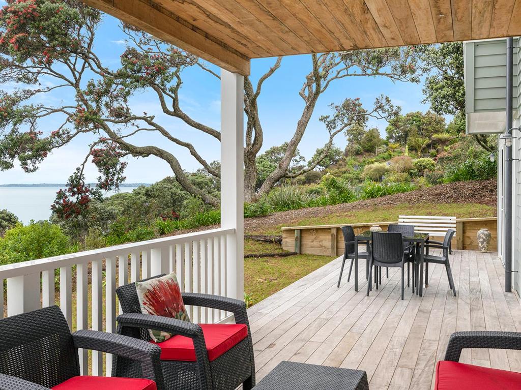 un portico con sedie e tavolo con vista sull'oceano di MaiMoana - Hatfields Beach Cliff-Top Retreat a Orewa