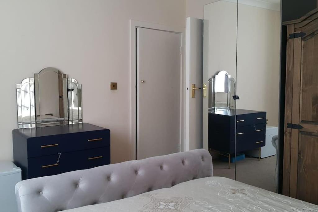 um quarto com uma cama, uma cómoda e um espelho em Primary bedroom with king size bed in 3 rooms apartment em Londres