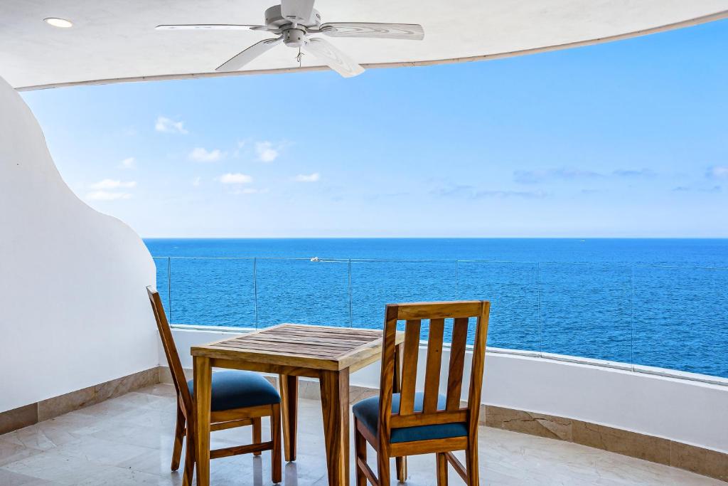 a table and chairs on a balcony with the ocean at Blue Horizon 801 in Puerto Vallarta