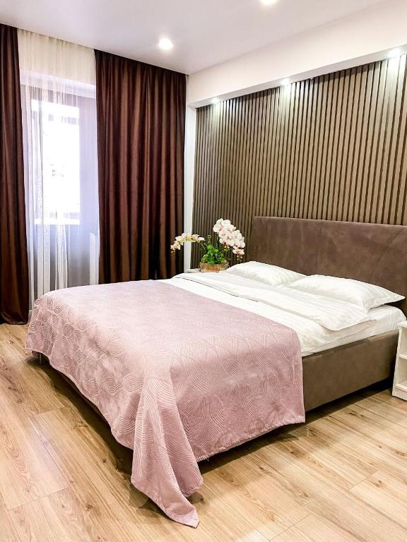 a bedroom with a large bed with a pink blanket at Central City Apartments in Ustʼ-Kamenogorsk