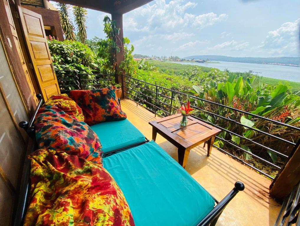 a porch with a couch and a table on a balcony at Home On The Nile water front Cottage in Jinja