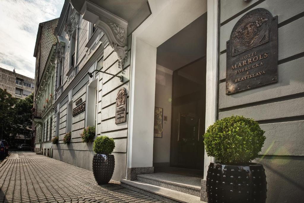 ein Gebäude mit zwei Topfpflanzen auf einer Straße in der Unterkunft Marrol's Boutique Hotel in Bratislava