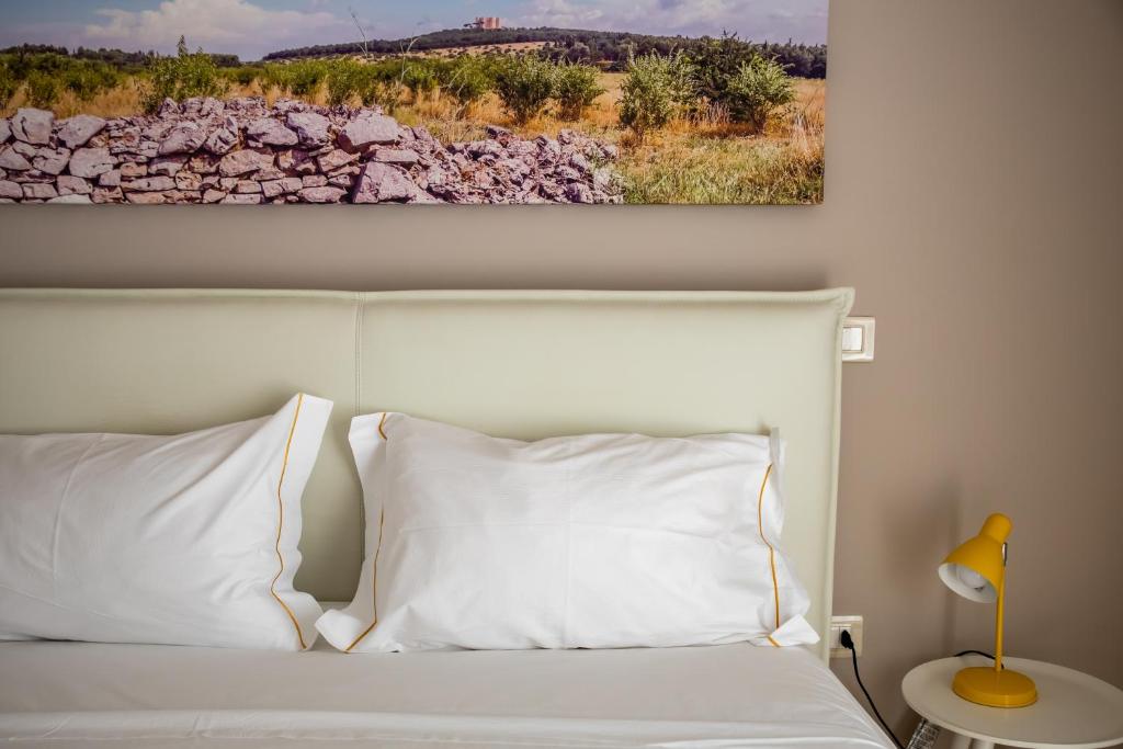 - un lit avec des oreillers blancs et un tableau mural dans l'établissement Borgomurgia, à Andria