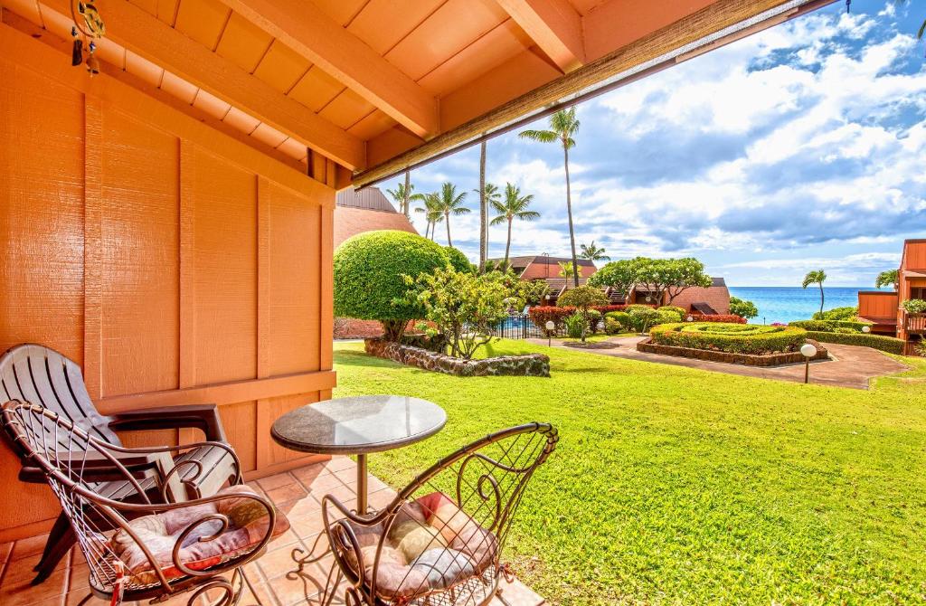 a porch with chairs and a table and a view of the ocean at Kuleana Resort 209 in Kahana