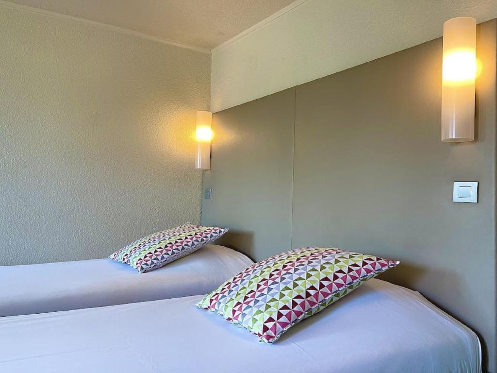 two beds in a room with two pillows on them at Campanile Valence Sud in Valence