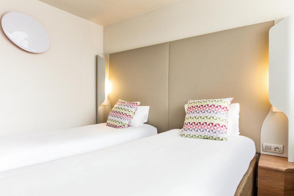 two beds in a room with two pillows at Campanile Valence Sud in Valence