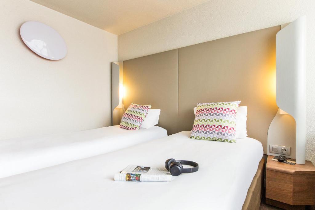 two beds in a hotel room with a book at Campanile Valence Sud in Valence