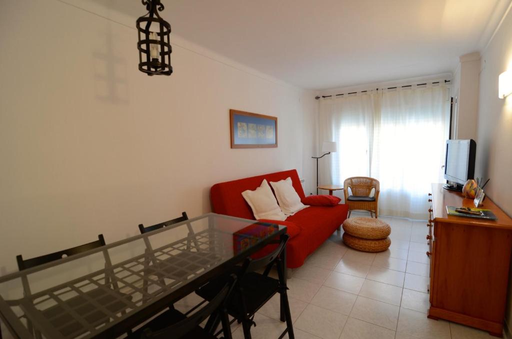 sala de estar con sofá rojo y TV en Enric Serra 54, en L'Escala