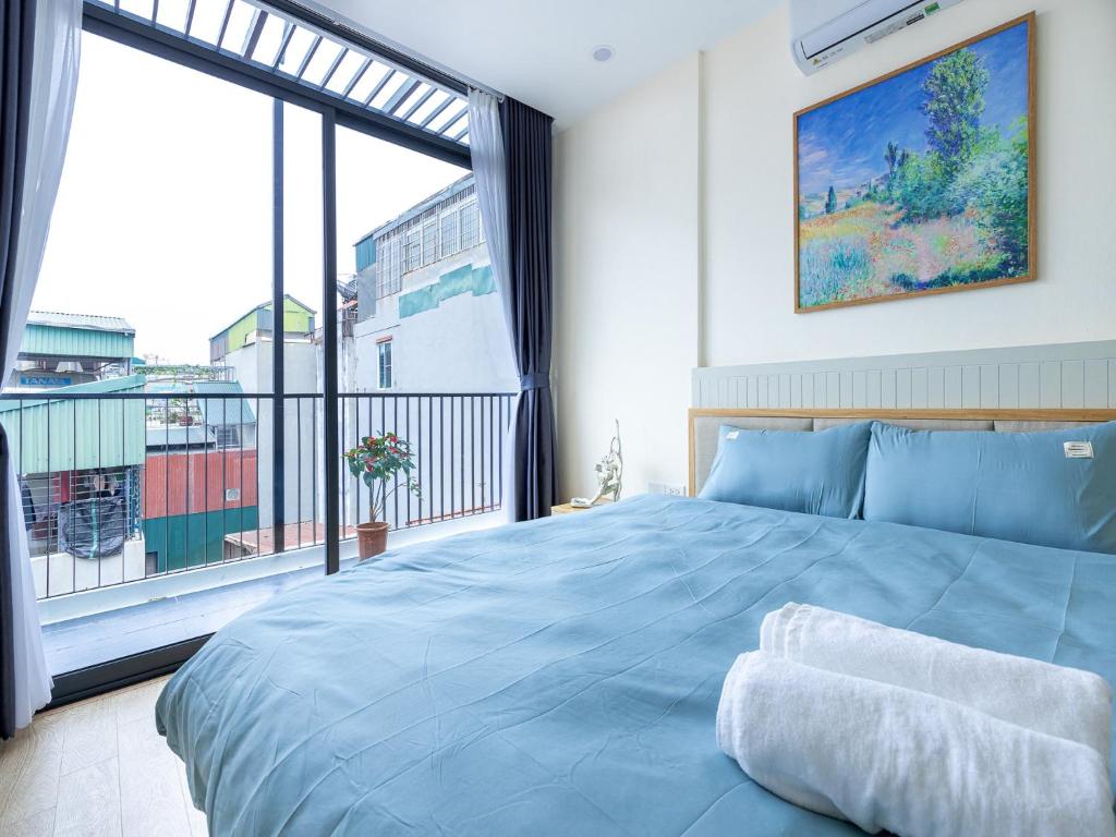 a bedroom with a blue bed and a large window at Muse Hanoi Boutique Apartment in Hanoi
