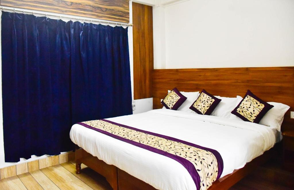 a bedroom with a large bed with blue curtains at Hotel Su Pinsa in Itānagar