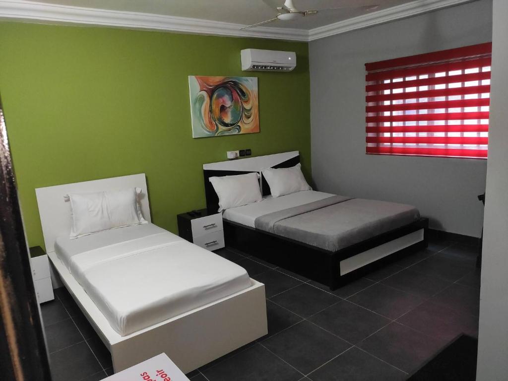 1 dormitorio con 2 camas y pared verde en Room in Guest room - Royal Blue Guest House Bar Deluxe Twin Bed, en Lomé