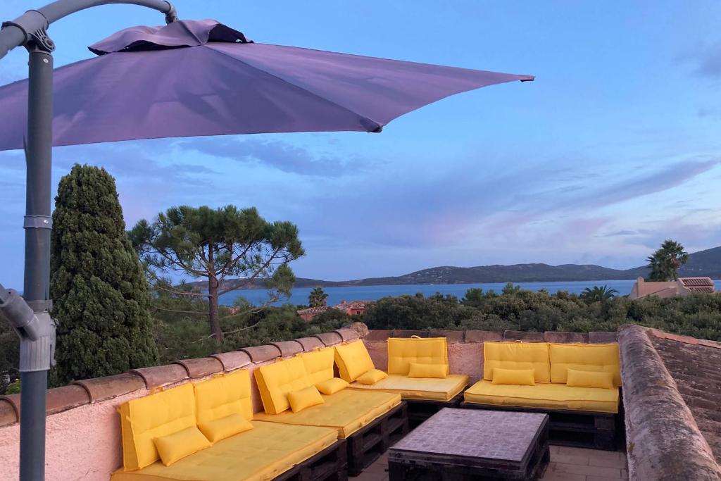 een patio met een bank en een parasol bij Grande Villa, Corse du Sud, Domaine privé de Cala Rossa in Porto-Vecchio