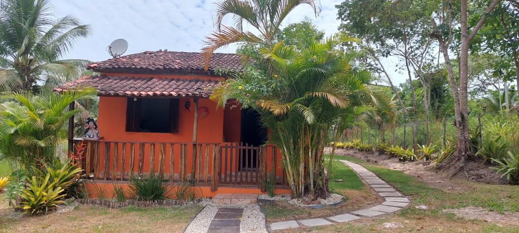 Casa temporada jaguaripe bahia toca do guaiamum في Jaguaripe: منزل برتقالي صغير مع سور وأشجار نخيل