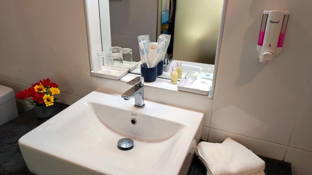 A compact bathroom vanity with a white sink, mirror and hotel toiletries.