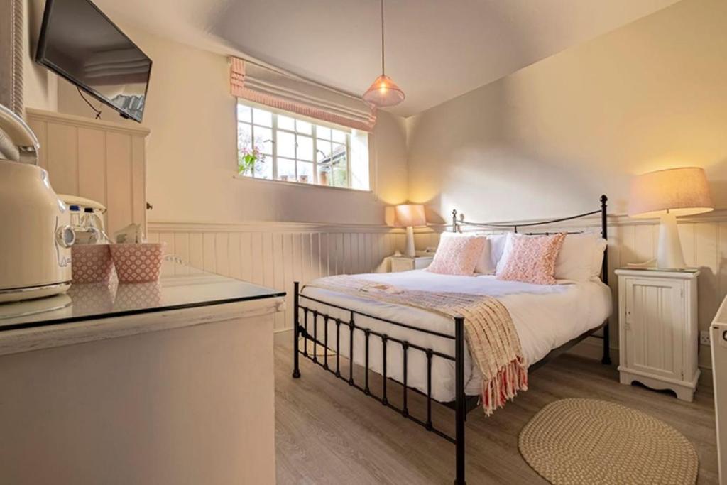 a bedroom with a bed with pink pillows on it at The Ship At Dunwich in Dunwich