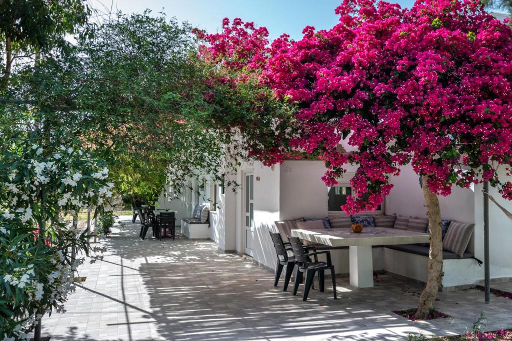 a table and chairs under a tree with pink flowers at Vrisidia Cottage - Nature, Seaview & Relax in Plakias