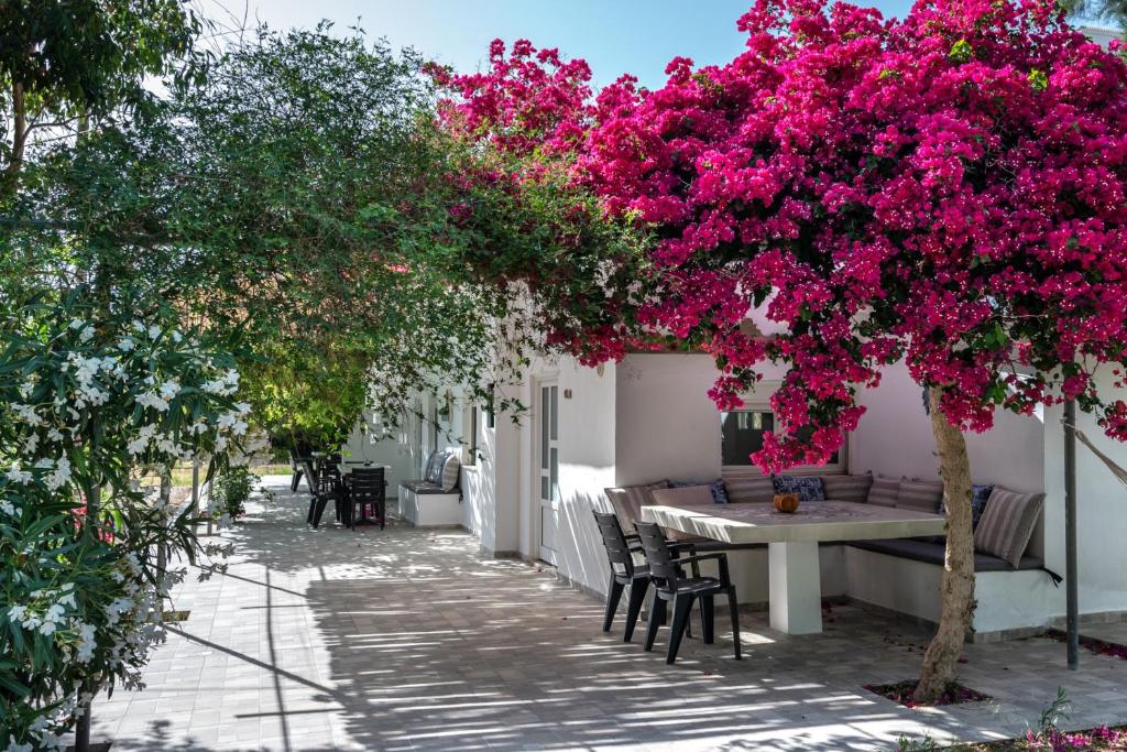 una mesa y sillas bajo un árbol con flores rosas en Vrisidia Cottage - Nature, Seaview & Relax, en Plakias