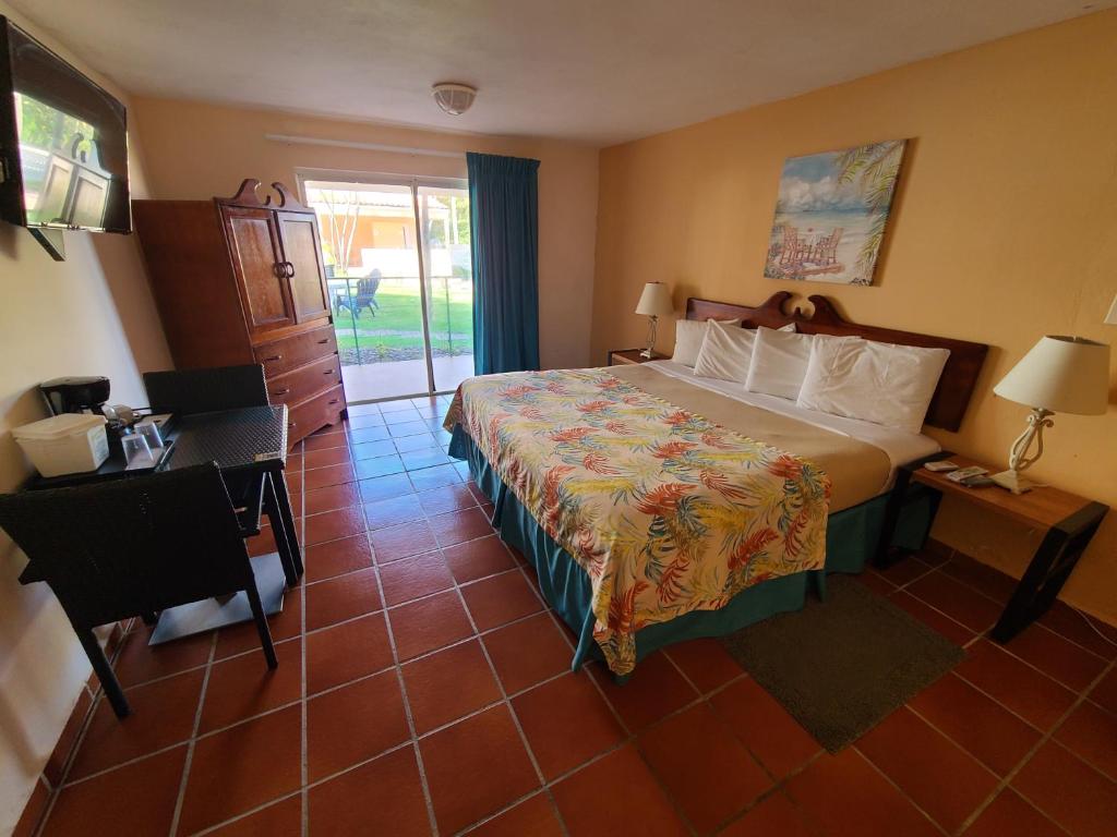 ein Hotelzimmer mit einem Bett und einer Tür zum Hof in der Unterkunft Parador Palmas de Lucia in Yabucoa