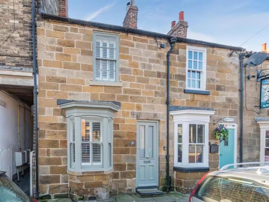 a brick house with white windows and a blue door at Stoney Nook Cottage in Guisborough