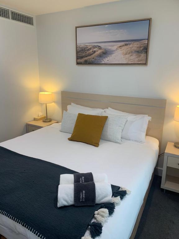 a bedroom with a large white bed with towels on it at Pier 108 Glenelg in Glenelg