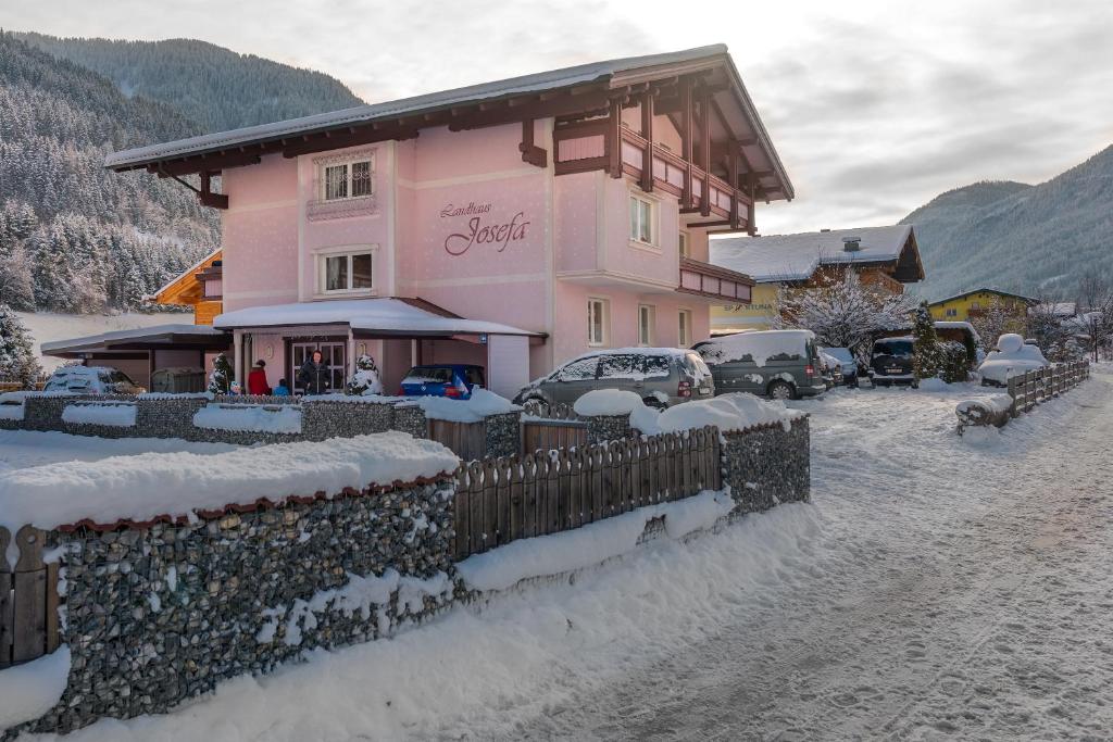 a pink house with a fence in the snow at Landhaus Josefa in Flachau