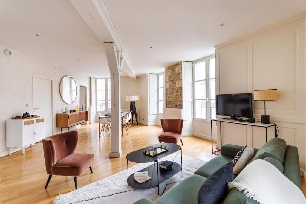 een woonkamer met een bank en stoelen en een tv bij La Tourelle & l'Honoré - 2 appartements dans le Centre historique de Rennes in Rennes