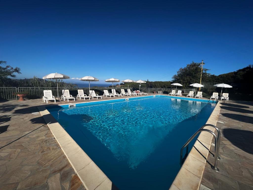 una piscina con sillas y sombrillas en Monolocali Le Lecce Pool & Tennis, en Capoliveri