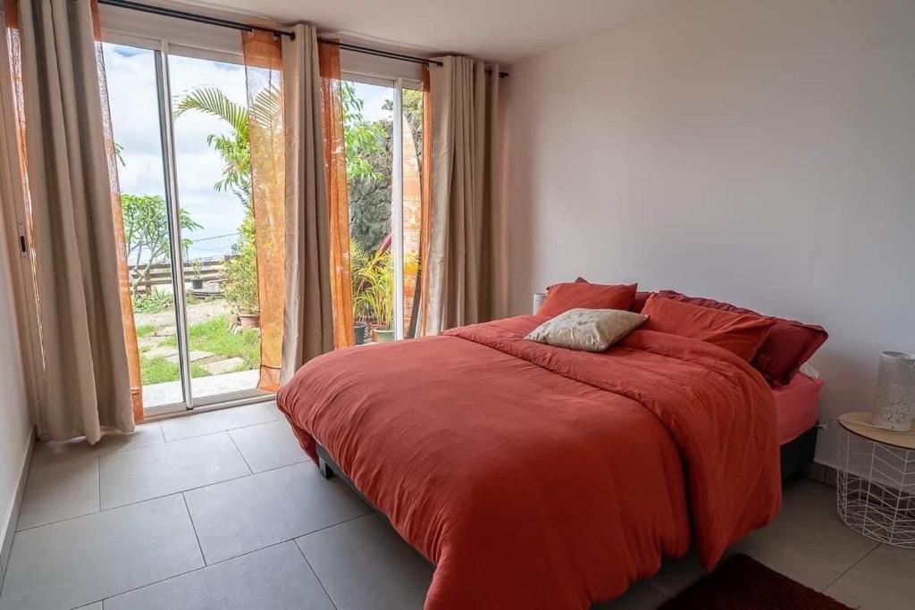 a bedroom with a red bed and a large window at Villa, Lossy in Le Tampon