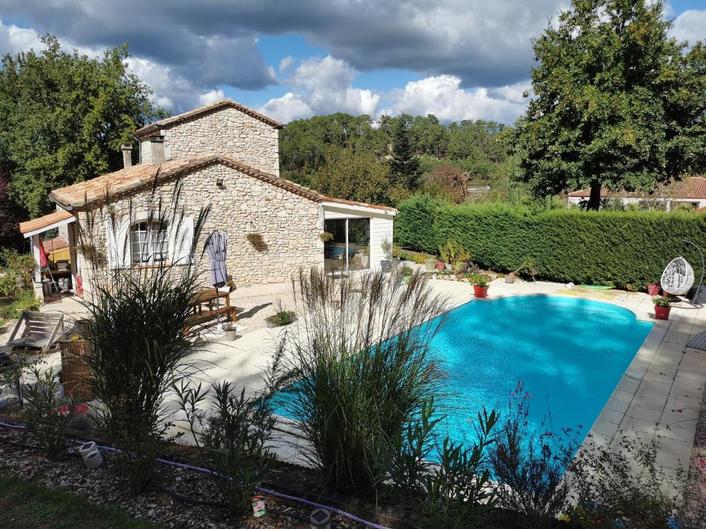 una gran piscina azul frente a una casa en DOMAINE DES 3 CYPRÈS Chambre PIVOINE Chez Nath & Pat, en Fumel