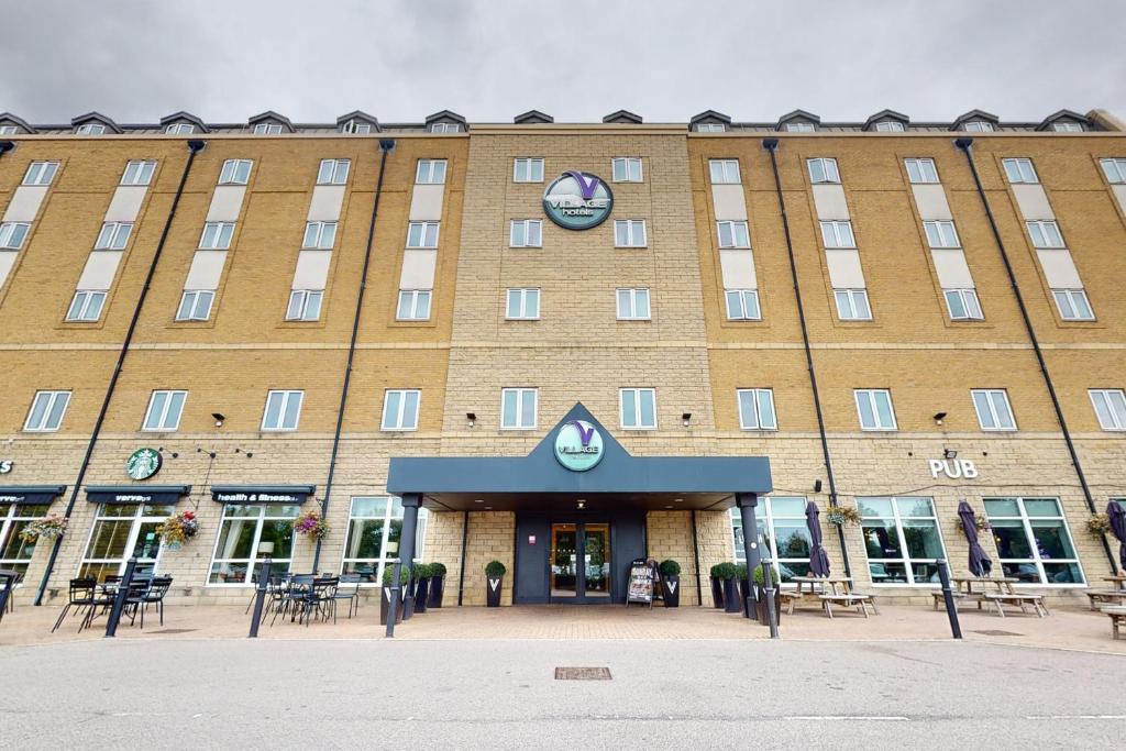 un gran edificio de ladrillo con mesas y sillas delante de él en Village Hotel Hull en Hull