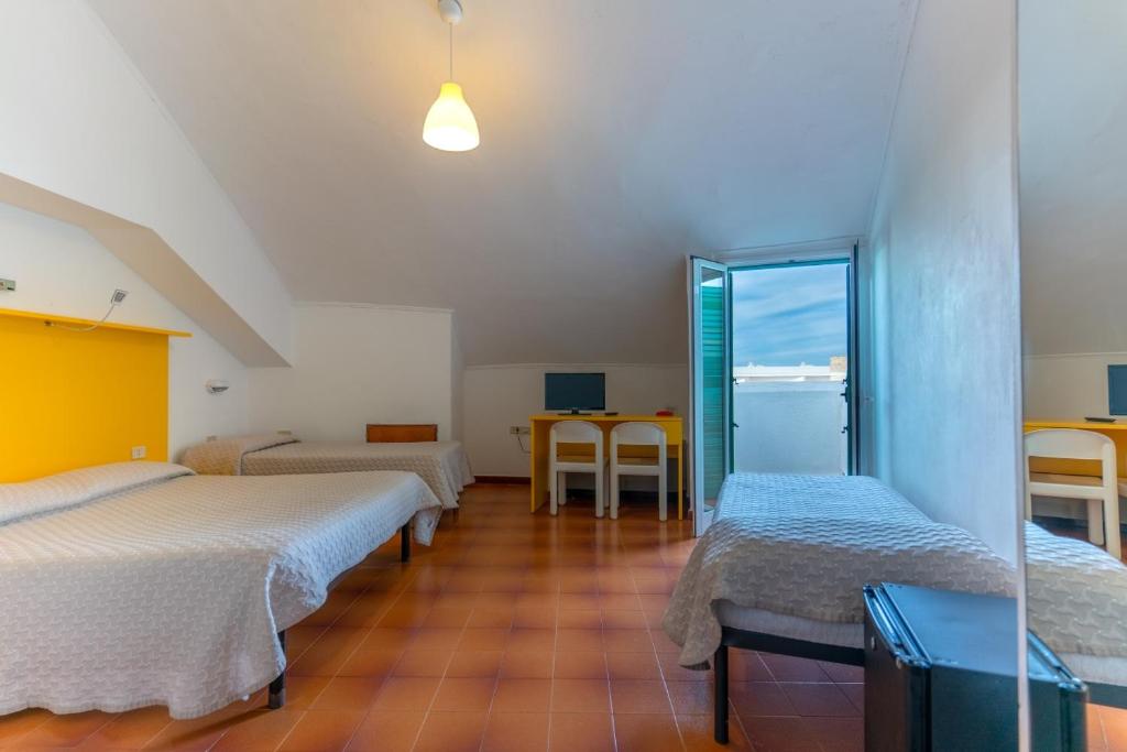 a room with three beds and a table with a view at Corvino Resort in Monopoli