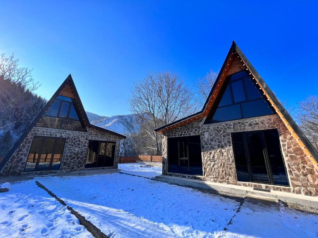 un bâtiment avec deux toits pointus dans la neige dans l'établissement Cottage Orcs, à Bordjomi