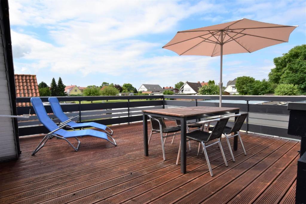 a wooden deck with a table and chairs and an umbrella at Fewo In dat Huus in Grube