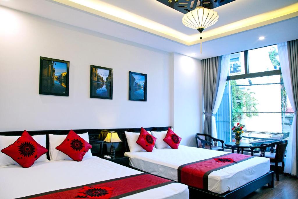 um quarto de hotel com duas camas com almofadas vermelhas em Green Sand Homestay em Hoi An