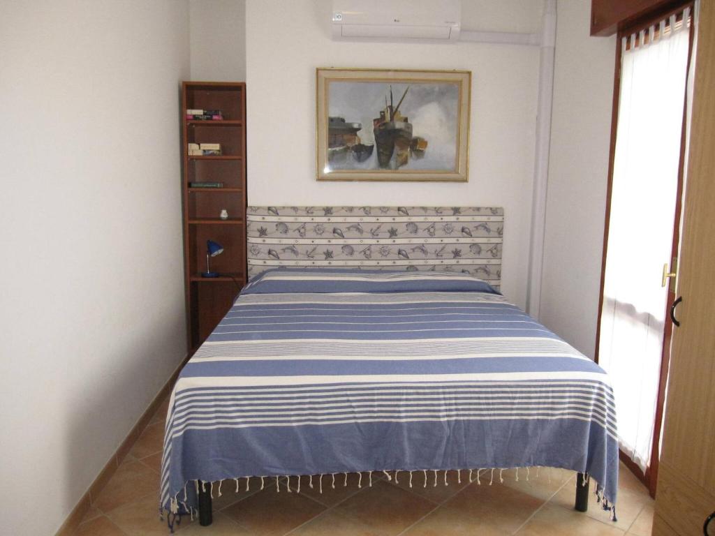 een slaapkamer met een bed met een blauwe en witte sprei bij Comfy flat with balcony at 30metres from the beach in Lido