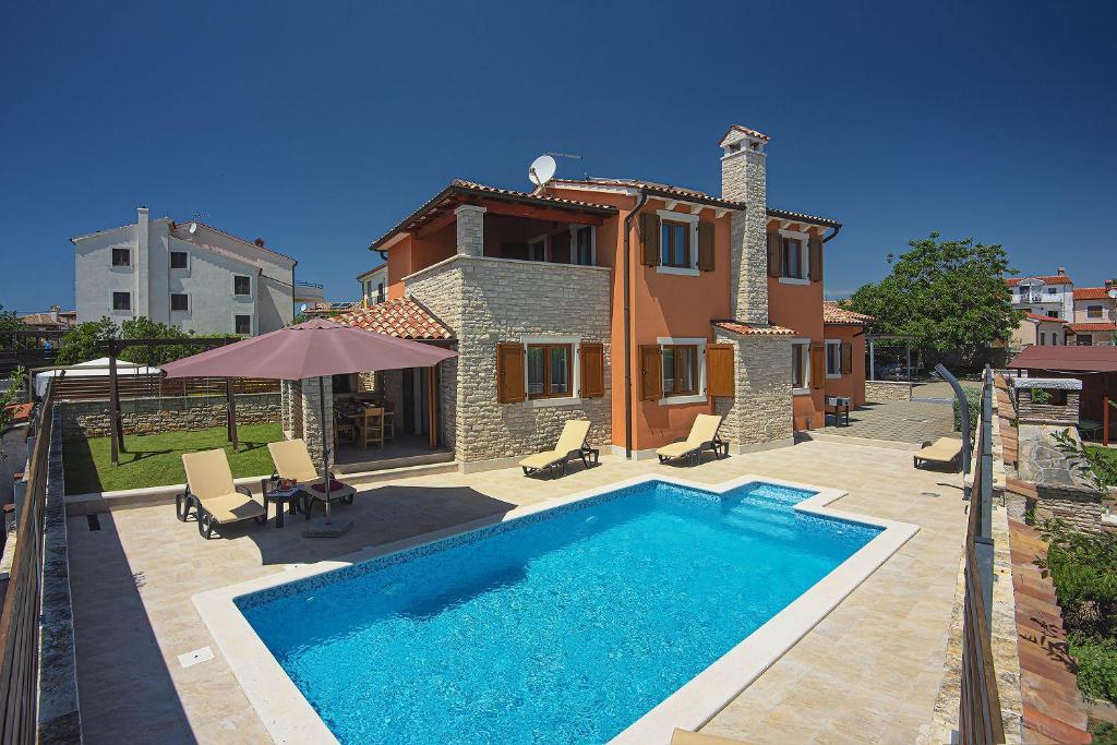 a villa with a swimming pool in front of a house at Villa nur 800 Meter zum Strand mit Meerblick, privatem Pool, BBQ und Spielplatz in Fažana