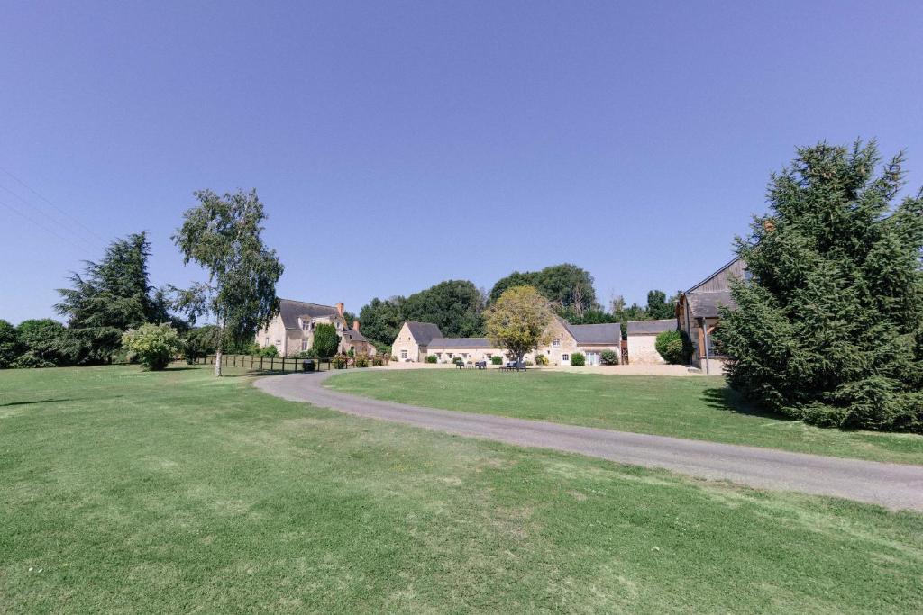 a house in a green yard with a driveway at Logis de Poëllier in Baugé-en-Anjou