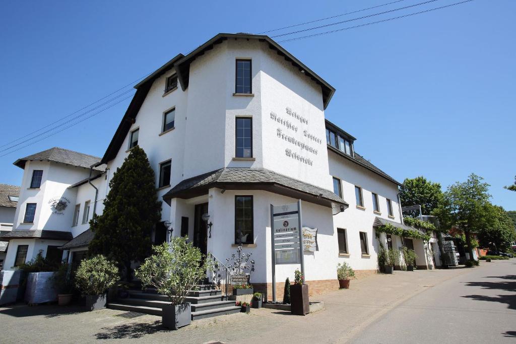 ein weißes Gebäude mit einem Schild davor in der Unterkunft Weingut Matthias Dostert / Culinarium in Nittel