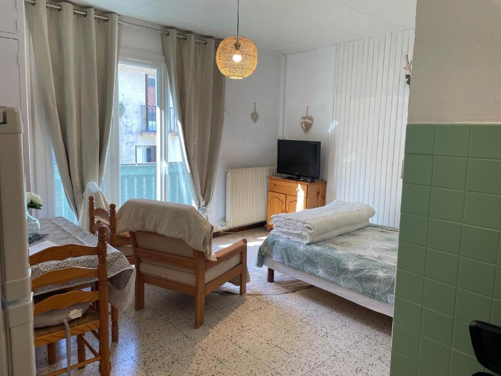 Schlafzimmer mit einem Bett, einem TV und einem Stuhl in der Unterkunft Studio amelie proche des thermes 2ieme étage in Amélie-les-Bains-Palalda