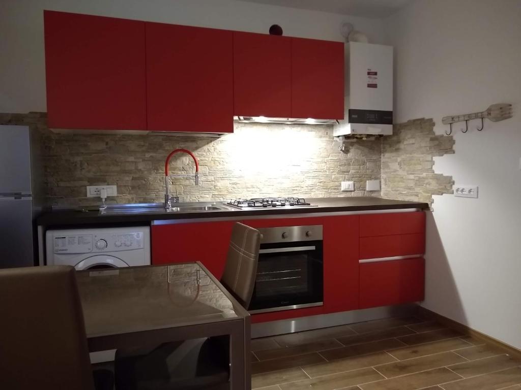 een keuken met rode kasten en een fornuis met oven bij al porticciolo in Trieste