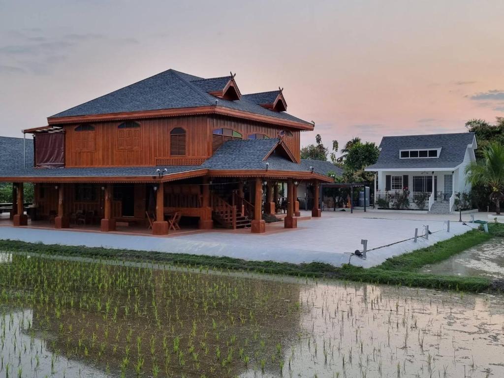 a large wooden building next to a body of water at MonMin Farmstay in Ban Mae Cho