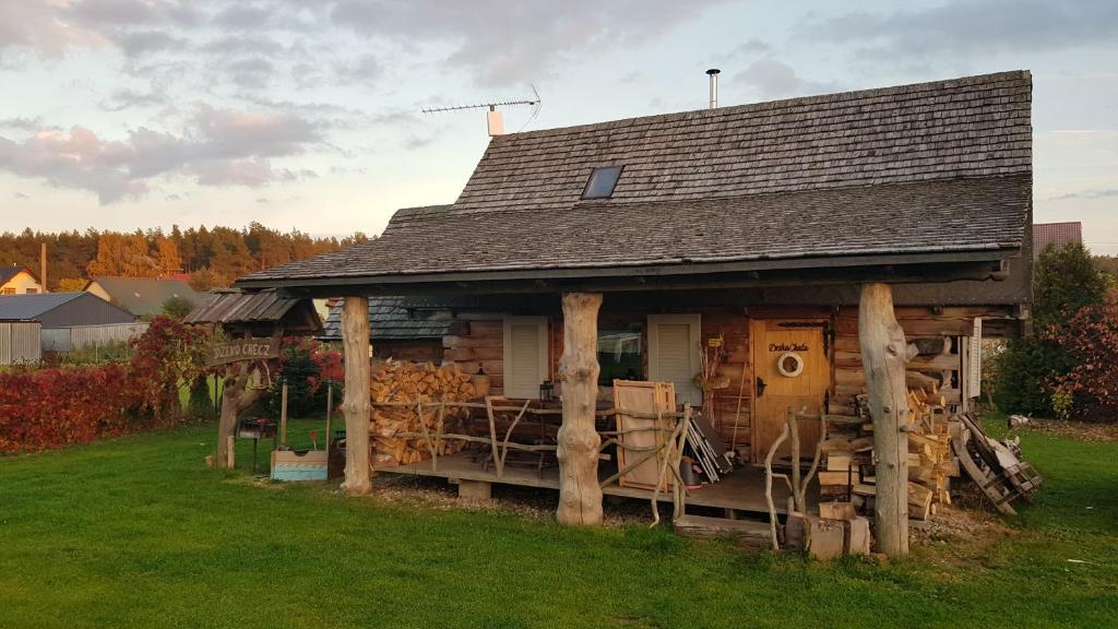 a house with a pile of logs in the yard at Dzika Chata in Nowy Barkoczyn