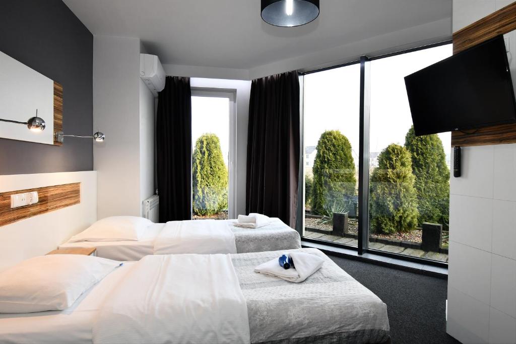 two beds in a hotel room with a large window at Sleepinn Gdansk Airport in Gdańsk-Rębiechowo