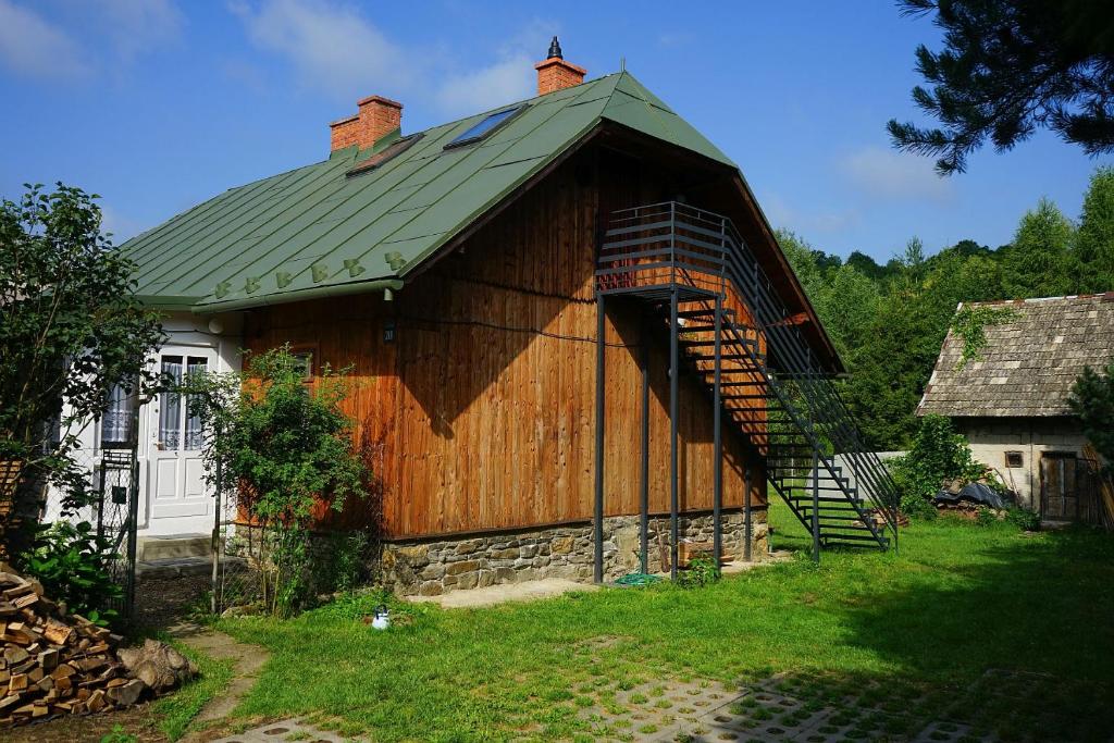 une grande grange en bois avec un toit vert et un escalier dans l'établissement Karolówka Nad Osławą, à Czaszyn