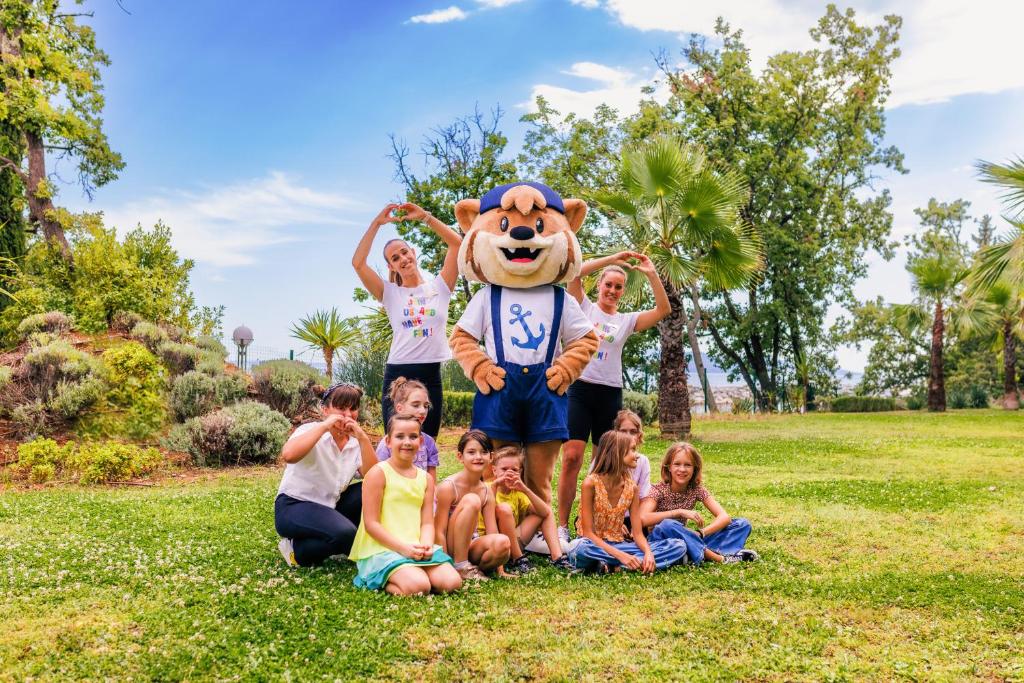 a family posing with a mascot in a park at Hotel Excelsior - Liburnia in Lovran