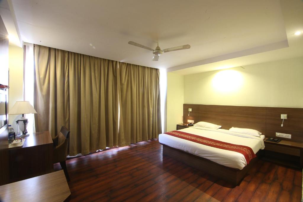 a bedroom with a bed and a desk and curtains at HOTEL GARNET in Durg