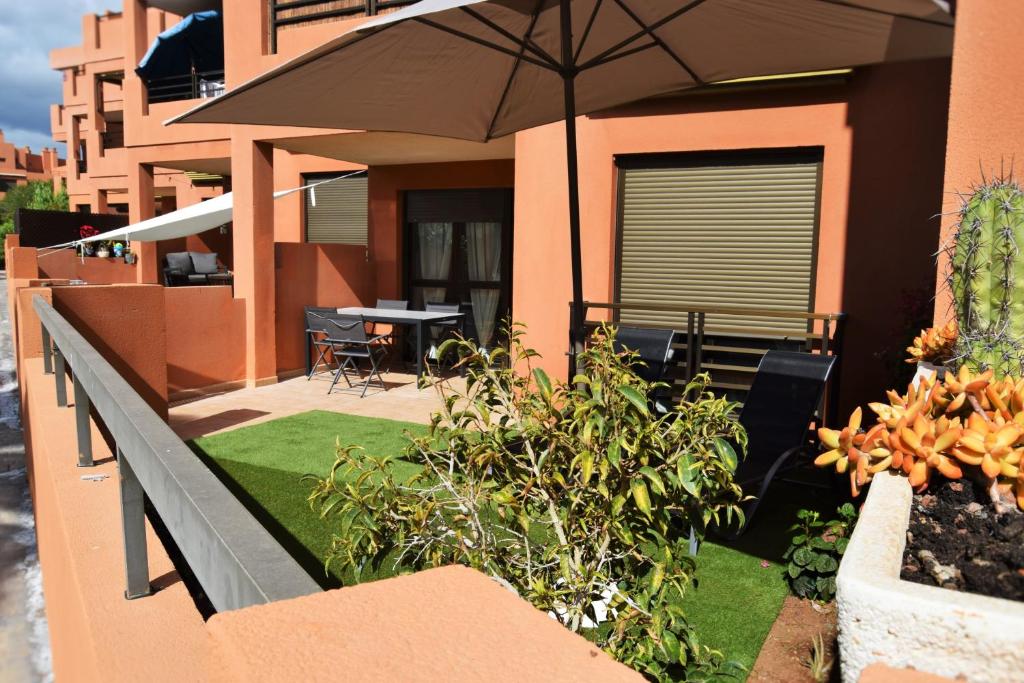 un balcón de una casa con sombrilla y césped en Sotavento Tejita, terrace and beach, en La Tejita
