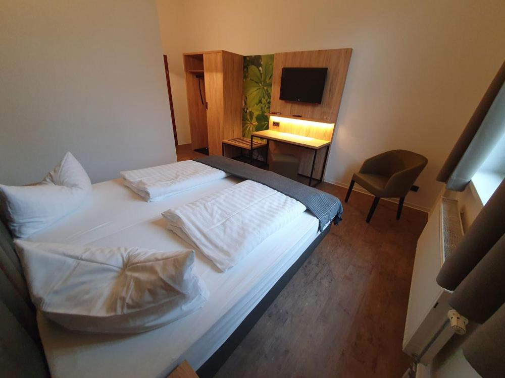 a bedroom with two beds and a desk and a television at Gasthaus &amp; Hotel Grünhof in Frankfurt Oder